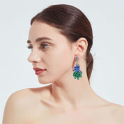 Elegant peacock-inspired dangle earrings featuring green crystal feather accents.